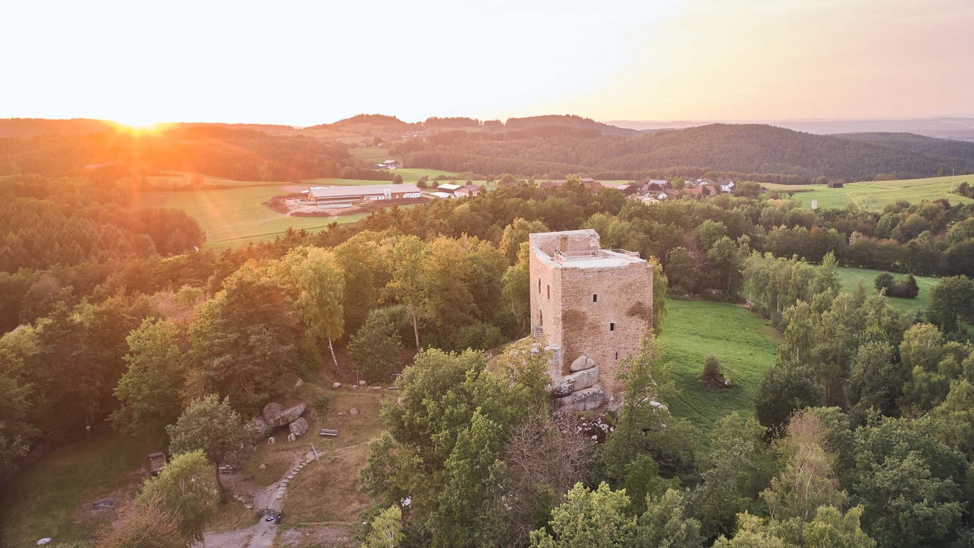 Sehenswertes rund ums Wellnesshotel Luftaufnahme der Burgruine Lobenstein bei Sonnenuntergang im Bayerischen Wald nahe Cham – beliebtes Ausflugsziel in der Umgebung des Wellnesshotel Randsbergerhof in der Oberpfalz.