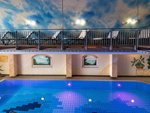 Our hotel with pool in Bavaria Hallenbad mit Liegebereich und Wandmalerei im Wellnesshotel Randsbergerhof in Cham, Bayerischer Wald – entspannter Badespaß in der Oberpfalz.